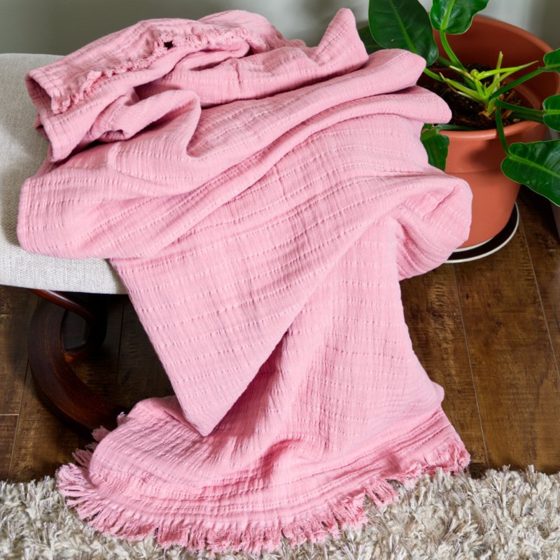 soft cotton throw in pink color draped on living room stool